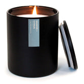 Bougie Calyan Wax Co Seaside & Citrus dans un verre noir mat, ambiance élégante.