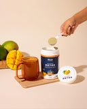 Bella All Natural Detox Mango mélangée dans un verre d'eau pour une boisson rafraîchissante.