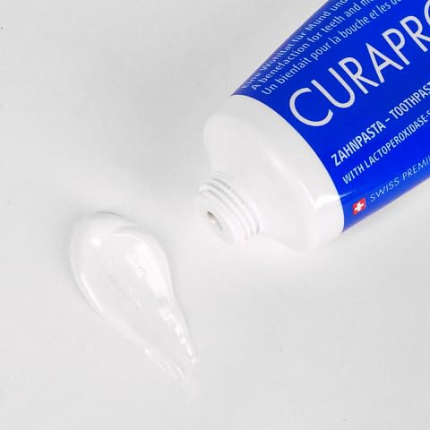 Tube de 75 ml et brosse à proximité, usage quotidien.