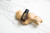 Flacon doTERRA Gingembre huile essentielle sur planche: ambiance chaleureuse et parfumée.
