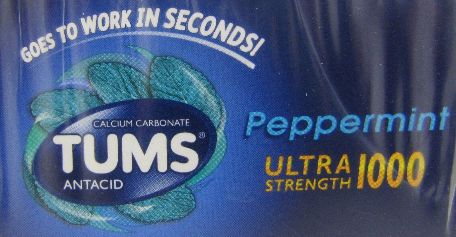 Main tenant une tablette GSK Tums Ultra Peppermint menthe, prête à être consommée rapidement.